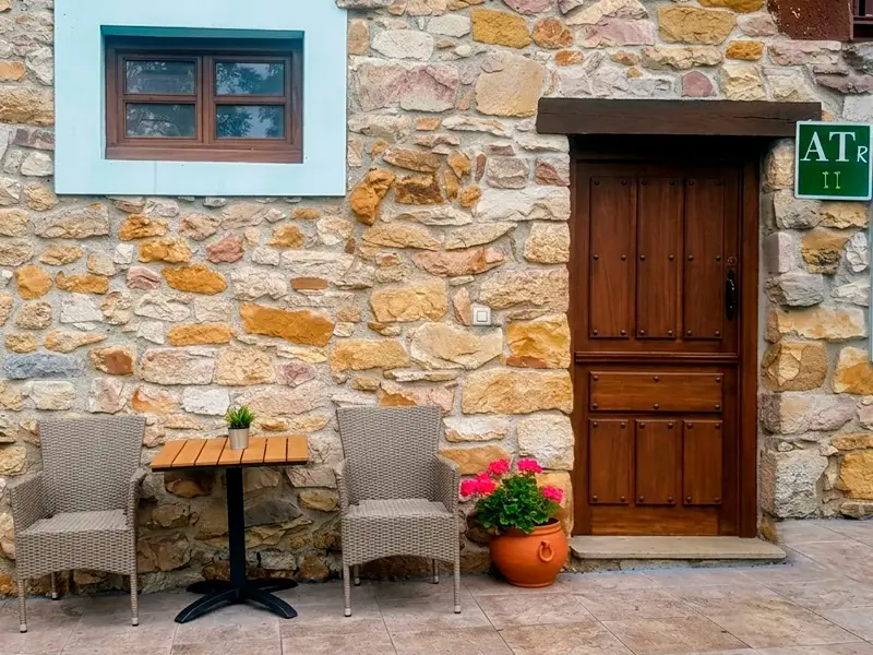 Exterior de los apartamentos turísticos con mesa y sillas.